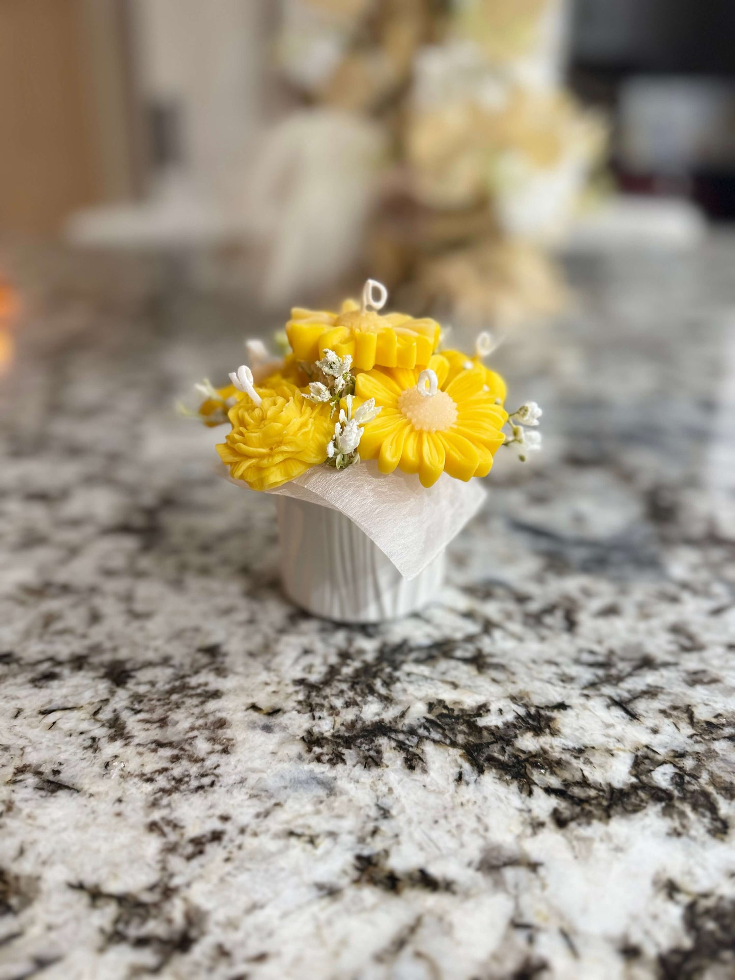 Small bouquet of yellow flowers in a white vase on a marble countertop