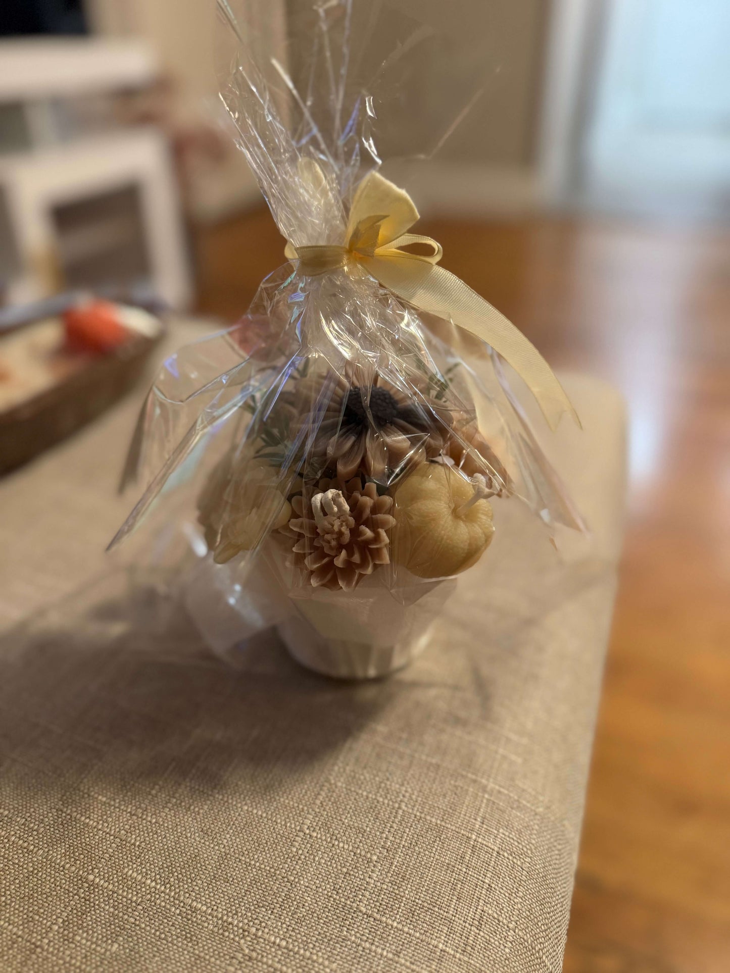 Floral candle bouquet — orange & ivory flowers, gift-wrapped in clear cellophane with cream ribbon