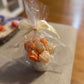 Floral candle bouquet — orange & ivory flowers, gift-wrapped in clear cellophane with cream ribbon