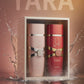 Two Yara perfume bottles with pink and red packaging on a decorative background with flowers and petals.