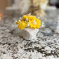 Small bouquet of yellow flowers in a white vase on a marble countertop
